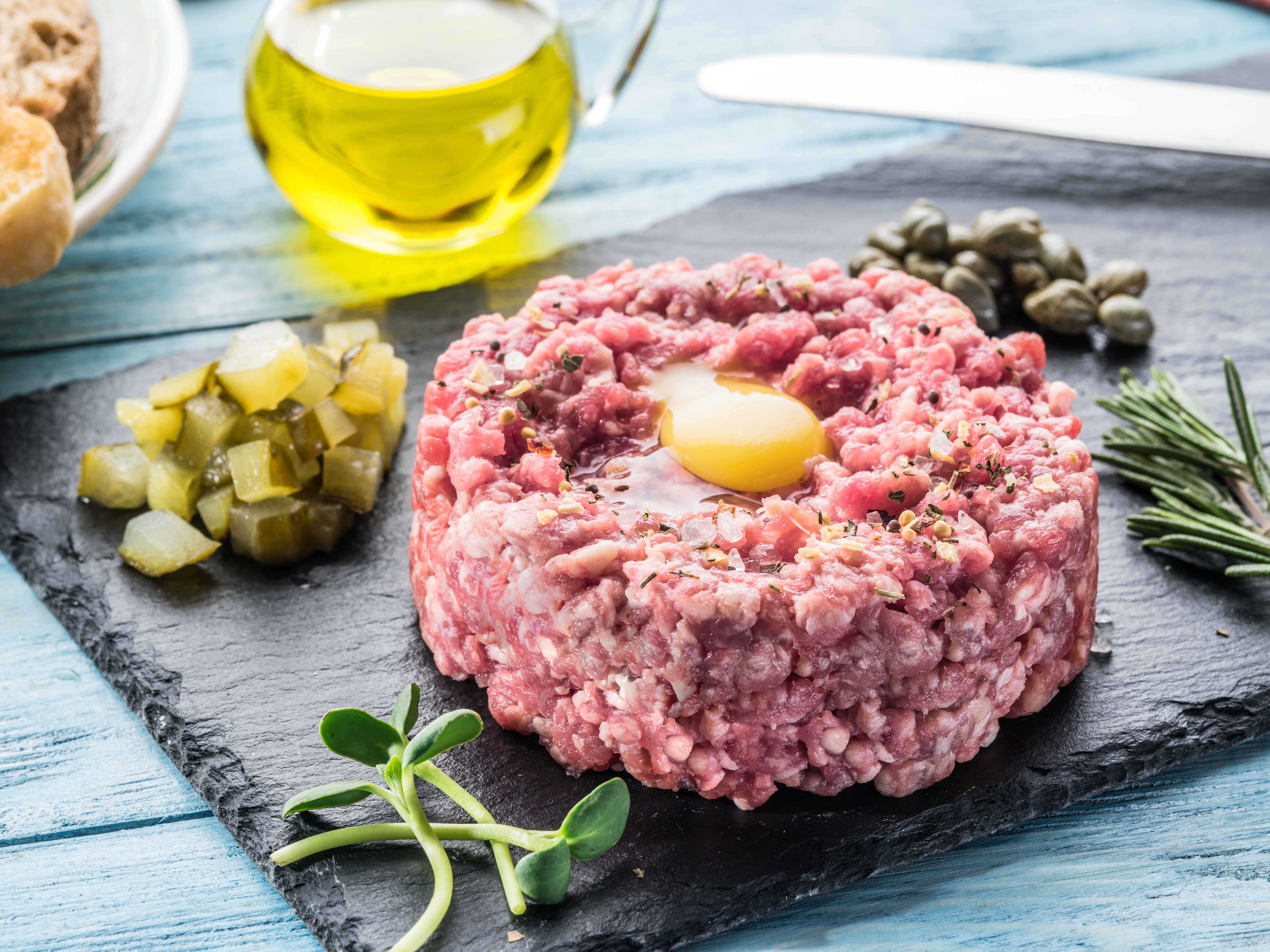 Steak tartare served with raw quail egg yolk, capers and bread. Meat dish.