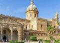 Esterno della Cattedrale di Palermo in una giornata di sole, con facciata storica, cupola e palme in primo piano.